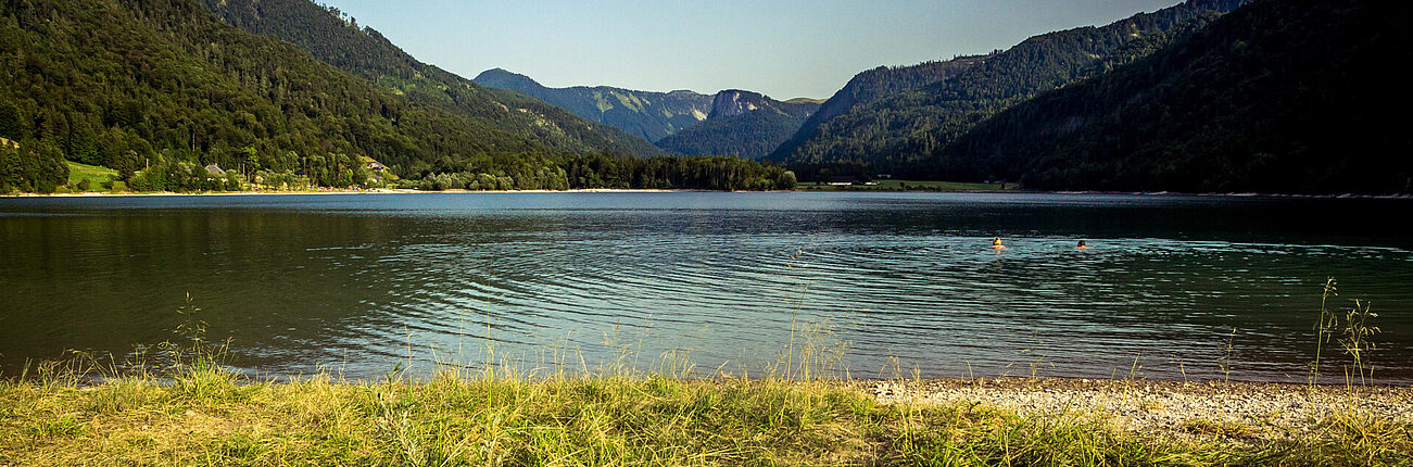 Ruhiger See mit sanften Wellen umgeben von grünen Bergen