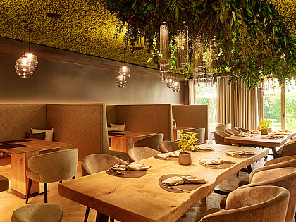 Modern restaurant with wooden tables, green decor, and pendant lighting